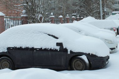 Kışın bir şehir caddesinde araba karla kaplı.