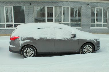 Kışın bir şehir caddesinde araba karla kaplı.