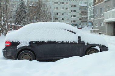 Kışın bir şehir caddesinde araba karla kaplı.