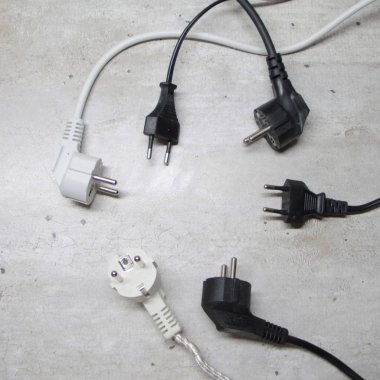 Kablolu elektrik prizleri bir dairenin gri yüzeyinde yatar.