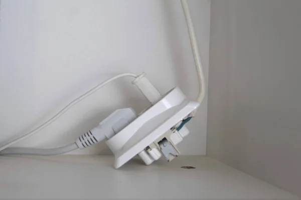 Two electrical plugs are plugged into a broken outlet — 스톡 사진