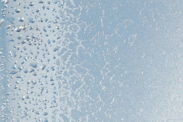 Blå fönster glas täckt hes is mönster textur med vattendroppar. Kall natur vinter bakgrund — Stockfoto