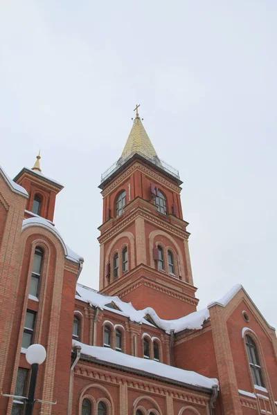 Fragment d'une église en brique rouge avec fenêtres et toit doré — Photo