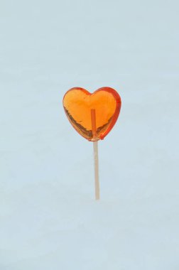 Kırmızı kalp şekilli lolipop çubukları kışın kardan çıkar.