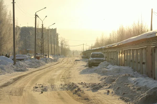 俄罗斯城市街道上，雪堆、砖墙和老旧预制房屋的背景下洒满了阳光. — 图库照片