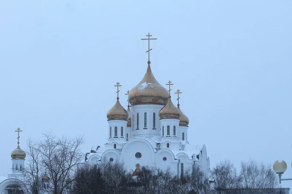 Cupole d'oro e croci di una chiesa cristiana ortodossa bianca contro il cielo — Foto Stock