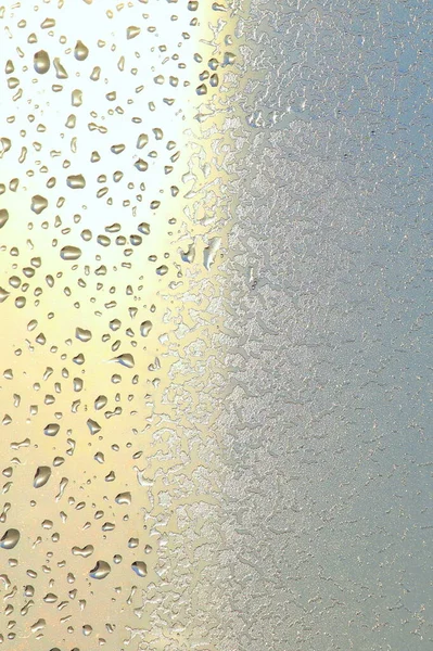 Vidrio de ventana azul cubierto de textura de patrón de hielo de escarcha con gotas de agua. Naturaleza fría fondo de invierno — Foto de Stock