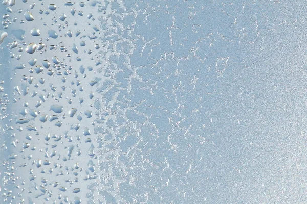 Blauw vensterglas bedekt met vorst ijs patroon textuur met waterdruppels. Koude natuur winter achtergrond — Stockfoto