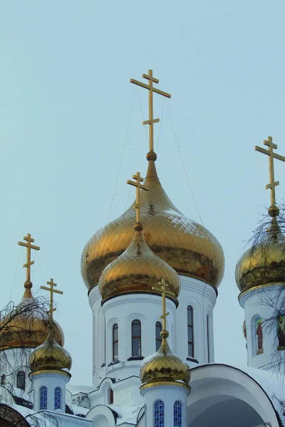 Golden domes and crosses of a white Orthodox Christian church against the sky — Stockfoto