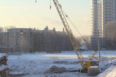 Large crawler crane works at a construction site on a frosty sunny day in winter in Russia