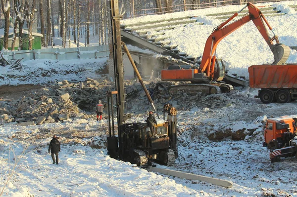 Excavator loads soil into a truck at a construction site in winter in Russia — ストック写真