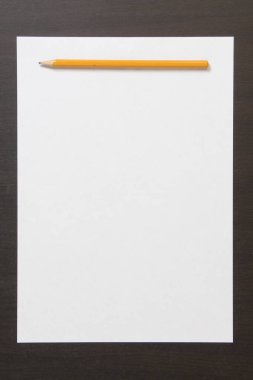 Koyu renkli ahşap arka planda beyaz kağıt ve kalem şablonu. İş planı ve strateji kavramı, içeriğin geliştirilmesi ve uygulanması. Metin için boş alanı olan stok fotoğrafı. 