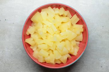 Kırmızı seramik bir tabakta ananas dilimleri gri bir zemin üzerinde mermer çatlaklar ve lekelerle. Sağlıklı beslenme kavramı, yaz havası. Web, baskı, arkaplan ve duvar kağıdı için stok fotoğrafı.