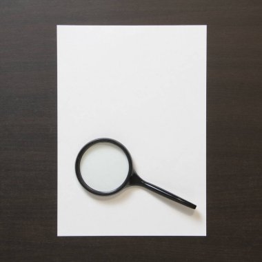 Koyu renkli ahşap zemin üzerinde magnefy olan beyaz kağıt şablonu. Arama, tespit etme ve sorunları çözme kavramı. Metin ve tasarım için boş alanı olan stok fotoğrafı.