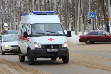 15-02-2020 Syktyvkar, Rusya. Mavi ışıklı kırmızı beyaz bir ambulans kışın şehir caddesi boyunca yol alır..
