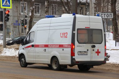 15-02-2020 Syktyvkar, Rusya. Mavi ışıklı kırmızı beyaz bir ambulans kışın şehir caddesi boyunca yol alır..