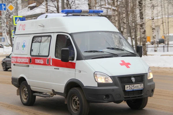 15-02-2020 Syktyvkar, Rusya. Mavi ışıklı kırmızı beyaz bir ambulans kışın şehir caddesi boyunca yol alır..