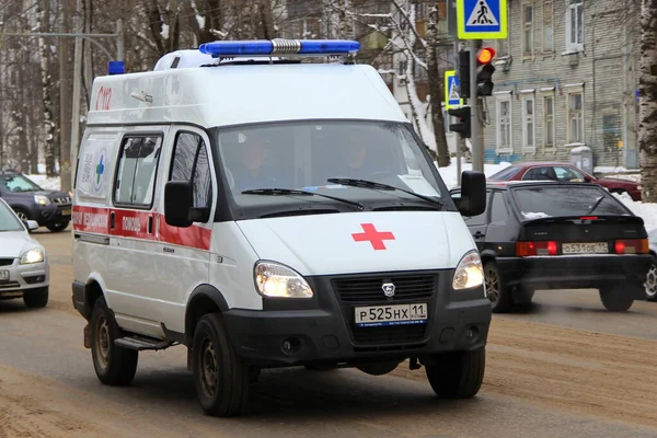 15-02-2020 Syktyvkar, Rusya. Mavi ışıklı kırmızı beyaz bir ambulans kışın şehir caddesi boyunca yol alır..