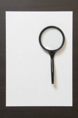 Koyu renkli ahşap zemin üzerinde magnefy olan beyaz kağıt şablonu. Arama, tespit etme ve sorunları çözme kavramı. Metin ve tasarım için boş alanı olan stok fotoğrafı.