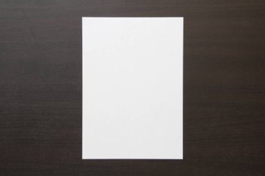 Koyu renkli ahşap zemin üzerine beyaz kağıt şablonu. Yeni fikir, iş planı ve strateji kavramı, içeriğin geliştirilmesi ve uygulanması. Metin için boş alanı olan stok fotoğrafı.