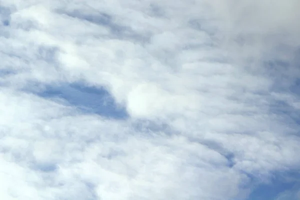 Cloudy blue sky with white and gray clouds. Background for text and design.