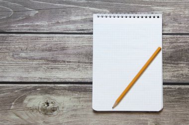 Tahta panoların arka planında basit grafit kalemle işaretleyici kağıdında boş beyaz bir sayfa bulunan bir not defteri var.