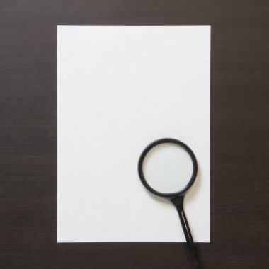Koyu renkli ahşap zemin üzerinde magnefy olan beyaz kağıt şablonu. Arama, tespit etme ve sorunları çözme kavramı. Metin ve tasarım için boş alanı olan stok fotoğrafı.