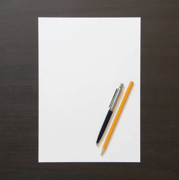 Plantilla de papel blanco con pluma y lápiz sobre fondo de madera color wengué oscuro . —  Fotos de Stock
