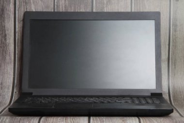 A laptop with a empty screen stands on the background of wooden boards. Place for text, layout for design