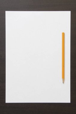 Koyu renkli ahşap arka planda beyaz kağıt ve kalem şablonu. İş planı ve strateji kavramı, içeriğin geliştirilmesi ve uygulanması. Metin için boş alanı olan stok fotoğrafı. 