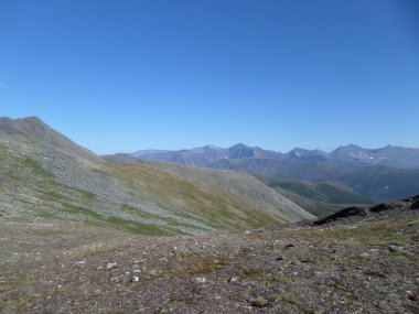 Tepeleri, vadileri, yeşil otları, kayaları ve gri taşları olan dağ manzarası. Rusya 'daki Ural Dağları' ndaki Yugydva Milli Parkı.