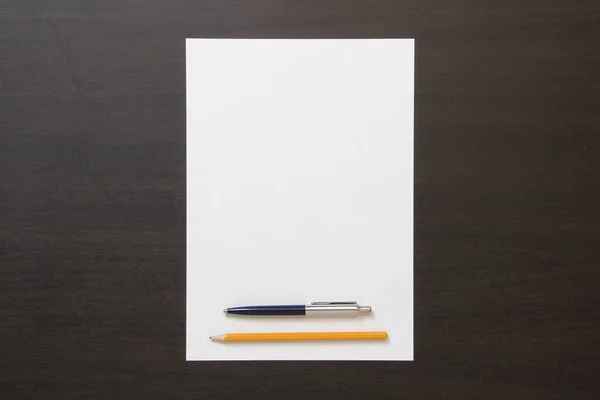 Koyu Renkli Ahşap Zemin Üzerinde Kalem Kalem Olan Beyaz Kağıt — Stok fotoğraf