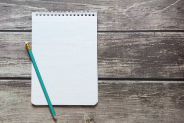 Tahta panoların arka planında basit grafit kalemle işaretleyici kağıdında boş beyaz bir sayfa bulunan bir not defteri var..