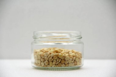 Beyaz arka planda bezelye aromalı cam kavanoz, yan görüş. Sağlıklı beslenme, diyet, vejetaryen ürünler kavramı. Metin ve tasarım için boş alanı olan stok fotoğrafı.