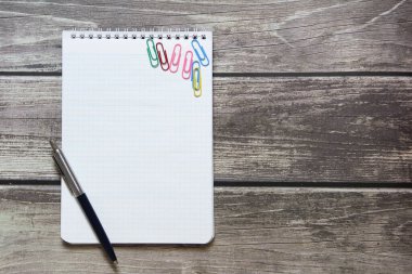 Dama kağıdında boş beyaz bir sayfa ve ataçla tahta tahtanın arka planında duran bir not defteri..