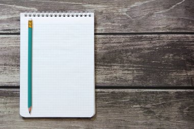 Tahta panoların arka planında basit grafit kalemle işaretleyici kağıdında boş beyaz bir sayfa bulunan bir not defteri var.