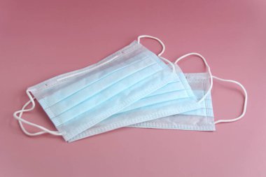 Pembe arka planda mavi renkli üç tıbbi maske var. Coronovirüs ilacı, sağlık ve salgın konsepti.