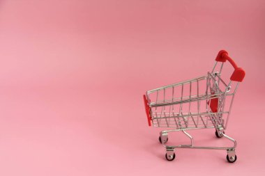 Pembe arka planda alışveriş sepeti olan küçük bir tramvay..