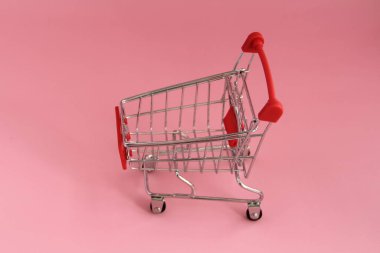 Pembe arka planda alışveriş sepeti olan küçük bir tramvay..