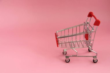 Pembe arka planda alışveriş sepeti olan küçük bir tramvay.