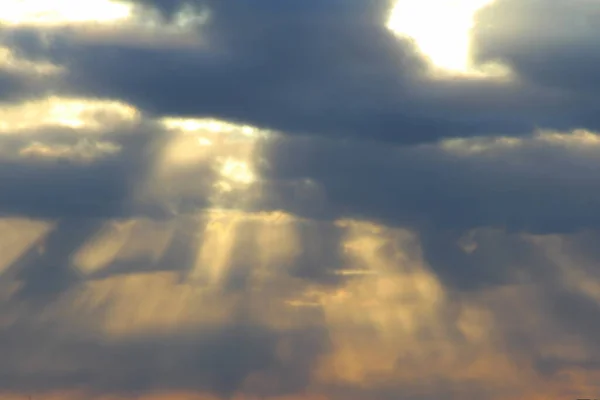 Die Sonne scheint bei Sonnenuntergang oder Sonnenaufgang hinter den Wolken durch. Die Sonnenstrahlen am Himmel — Stockfoto