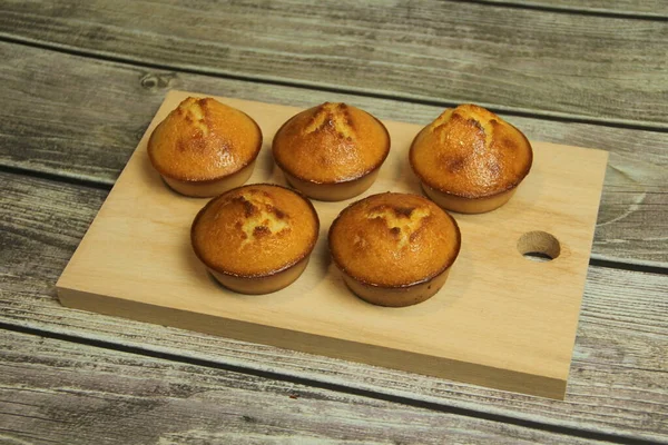 Five golden pies on a wooden board on a wooden table from boards