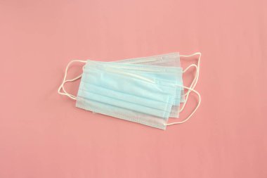Pembe arka planda tek kullanımlık tıbbi maskeler. Coronovirüs Salgını Savunma Kavramı