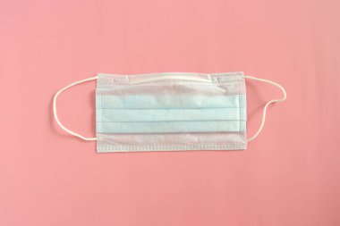 Pembe arka planda tek kullanımlık tıbbi maske. Coronovirüs Salgını Savunma Kavramı
