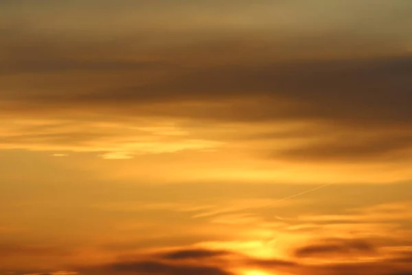 Sol nedanför horisonten och moln i den brinnande dramatiska orange himlen vid solnedgången eller gryningen bakgrundsbelyst av solen. Plats för text och design — Stockfoto