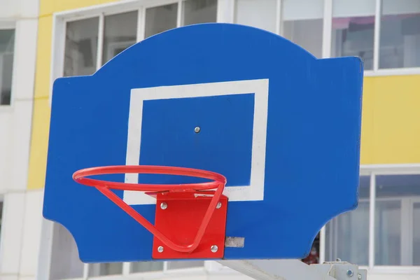 Červený basketbalový koš na modré desce na sportovním hřišti na ulici ve městě — Stock fotografie