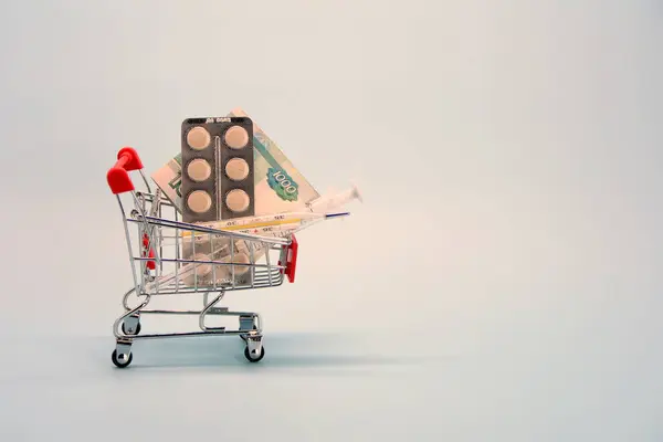 Shopping cart with pills, thermometer, syringe and money. The concept of medicine, insurance, shopping and expenses — Stock Photo, Image