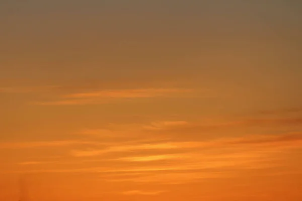 Sol debajo del horizonte y nubes en el cielo ardiente y dramático naranja al atardecer o al amanecer retroiluminado por el sol. Lugar de texto y diseño — Foto de Stock