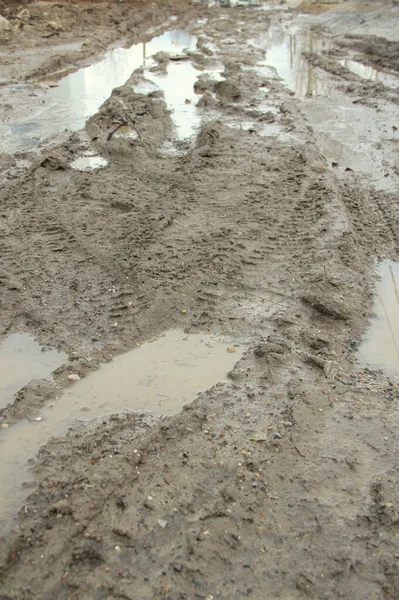 Chemin de terre sale avec piste, marques de roue, argile brune et flaques d'eau en Russie — Photo