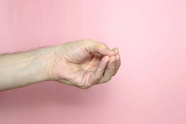 Main masculine à la peau claire montre un geste, main sur un fond rose clair — Photo
